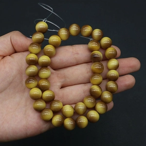 Close-up of yellow tiger eye glass beads with cat-eye effect for jewelry DIY making