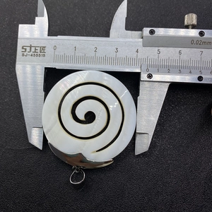 Calibre mostrando el diámetro de 44mm del colgante de nácar natural en espiral
