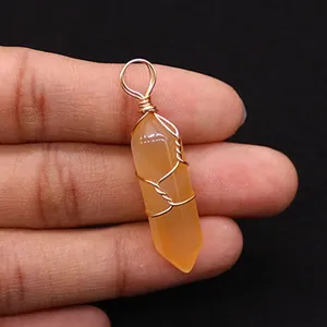 Macro detail of handmade wire wrapped orange crystal hexagonal prism stone pendant