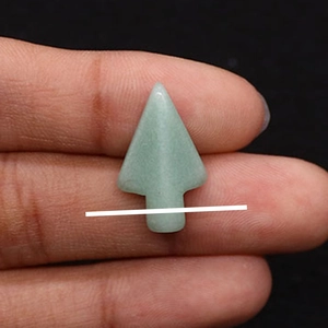 Macro detail van een turquoise pijlpunt hanger in de hand gehouden tegen zwarte achtergrond