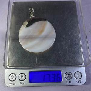 Vista macro que muestra el peso de 17,36 g del colgante de concha con fianza hueca