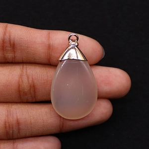 Detail of tear drop pink gemstone pendant held in hand with rose gold bail connector