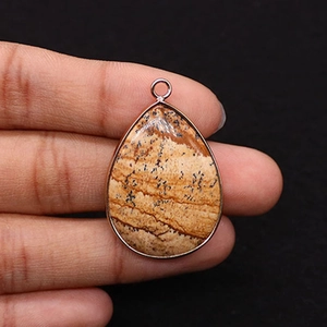 Macro view of teardrop natural stone pendant with picture jasper texture and metal edge