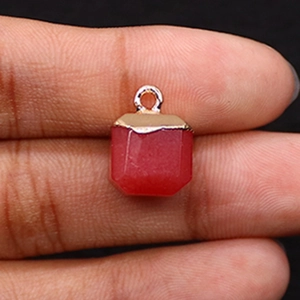 Macro detail of a red stone faceted cube pendant with a gold loop for DIY jewelry