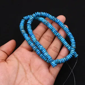 Dettaglio di perle turchesi piatte per la creazione di gioielli fai-da-te in mano