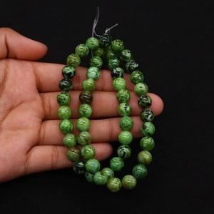Close-up of green natural stone beads with black spots for DIY jewelry making