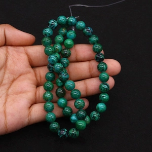 Macro shot of green imperial jasper round beads held in hand for jewelry making