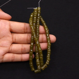 Gros plan de perles en pierre de bambou vert foncé pour la création de bijoux DIY