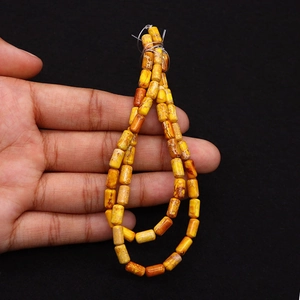 Dettaglio macro di perle cilindriche in pietra imperiale 4x8mm trama naturale gialla arancio