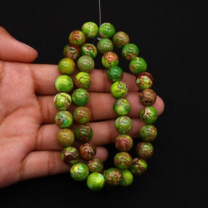 Macro detail of round green emperor stone beads held by hand for DIY jewelry making