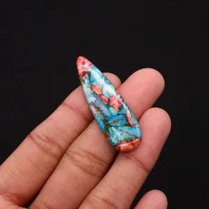 Macro shot of teardrop shaped blue and orange emperor stone pendant held by hand