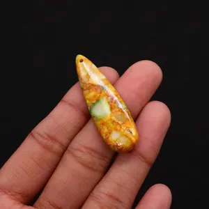 Macro detail of tear drop natural stone pendant with vibrant orange and green textures