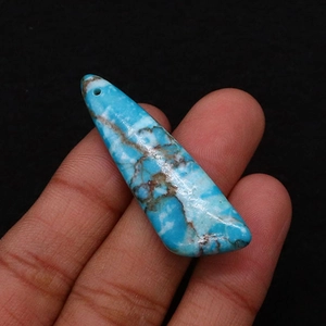 Macro shot of turquoise stone pendant detail with natural textures held by hand