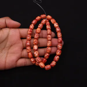 Dettaglio di perle a barilotto arancioni venate per creazione di gioielli fai-da-te
