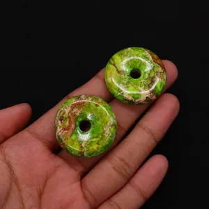Macro shot of two green emperor stone donut pendants showing natural mineral textures