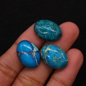 Primer plano de tres piedras de turquesa ovaladas pulidas con vetas negras en la mano