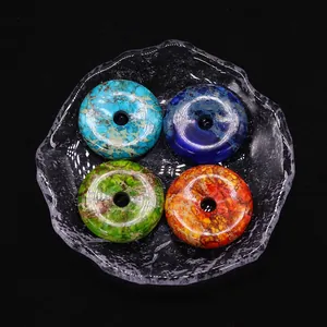 Set of four colorful round stone pendants with marble texture in a rippled glass dish