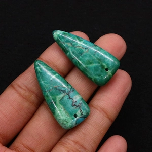 Macro detail of triangular turquoise pendants showing natural black matrix and iron veins