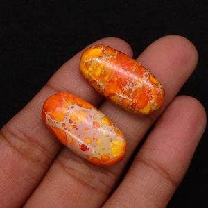 Close-up of vibrant orange and yellow oval emperor stone cabochons with web patterns