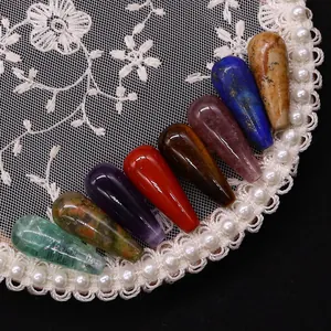 Pietre naturali levigate a forma di goccia in vari colori su pizzo bianco fine