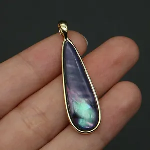 Primer plano de colgante gota dorado con incrustaciones de nácar violeta irisado