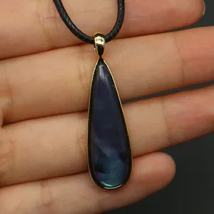 Detalle macro del colgante de gota en nácar púrpura con baño de oro y cordón negro