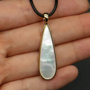 Detalle macro del colgante de nácar en forma de lágrima con borde dorado brillante