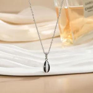 Detalle de collar con colgante de gota plateado y rayas blancas y negras sobre seda