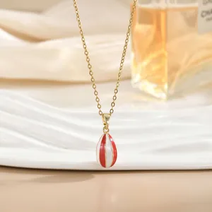 Primer plano de collar dorado con colgante de globo aerostático de esmalte a rayas rojas y blancas