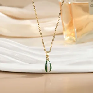 Detalle del collar con colgante de globo dorado y rayas de esmalte verdes y blancas