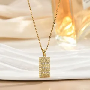 Collier avec pendentif lingot d'or, placage 18K et zircons sur fond blanc ondulé