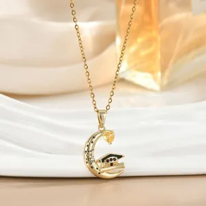 Detail van gouden halve maan ketting met afstudeerhoed en inspirerende tekst