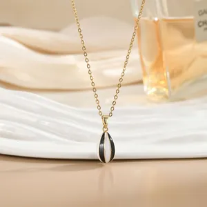 Detalle del collar bañado en oro con colgante de gota a rayas blancas y negras