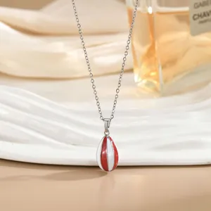 Detalle macro del collar con colgante de globo aerostático en esmalte rojo y blanco