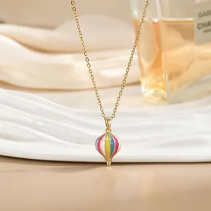 Detalle de un elegante collar con colgante de globo aerostático sobre raso blanco