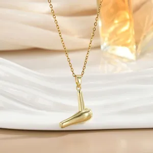 Detailed close-up of a golden mini hair dryer pendant on a delicate chain with silk texture