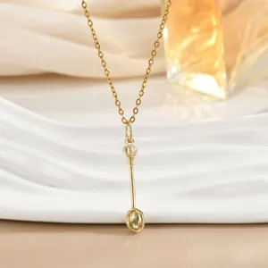 Detailed view of a golden crown spoon pendant on a delicate chain over a ceramic plate