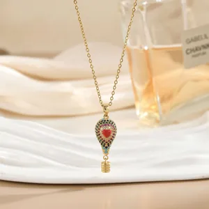Detalle del collar de globo aerostático dorado con piedras de colores y corazón
