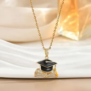 Detailopname van de gouden afstudeerhoed ketting met emaille en zirkonia inlegwerk