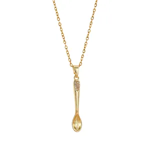 Golden crown tea spoon pendant necklace with zircon stones on a white background