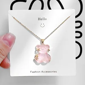 Detailansicht eines rosa Bärenanhängers an einer Goldkette auf einer Modekarte