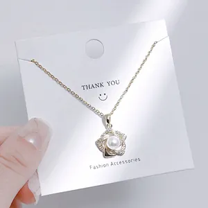 Nahaufnahme der goldenen Perlenblumen-Halskette auf einer weißen Geschenkkarte