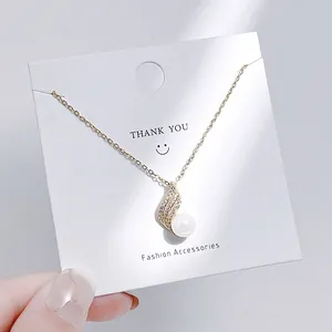 Detailaufnahme eines goldenen Schmetterlings-Anhängers mit Zirkonia-Steinen und weißer Perle