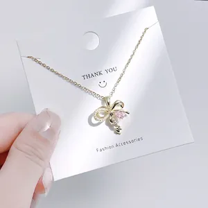 Detailaufnahme einer goldenen Schmetterling-Schlüsselkette mit rosa Herzstein auf Karte