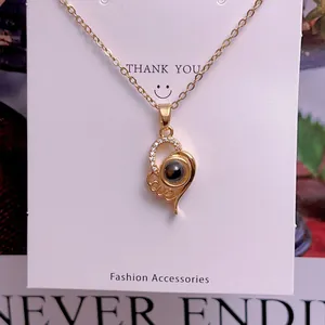 Macro detail of gold heart projection necklace with zircon accents and LOVE script
