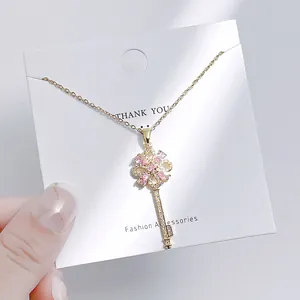 Nahaufnahme einer goldenen Schlüsselkette mit rosa Blütenblättern und funkelnden Kristallen
