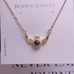 Detail of gold wing pendant necklace with central round bead on fashion jewelry card