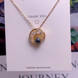 Macro shot of gold projection necklace featuring a moon ring pendant with small crystals