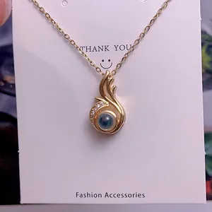 Detailed macro view of gold-plated flame pendant with a deep blue bead and white crystal accents