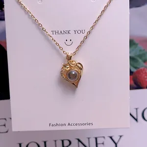 Detail of gold heart pendant necklace with projection stone on white display card